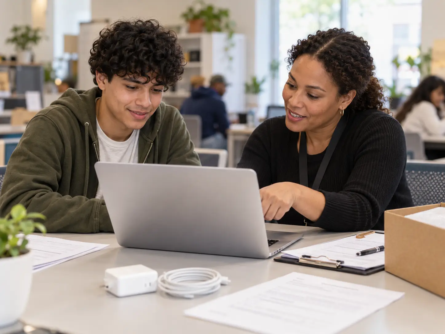 Adult reviewing a premium refurbished silver laptop with a technology program staff member